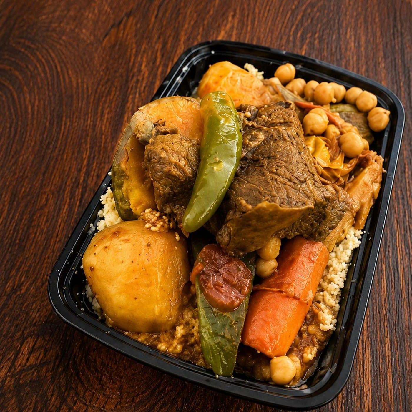 A platter of couscous topped with braised meat, vegetables and chickpeas