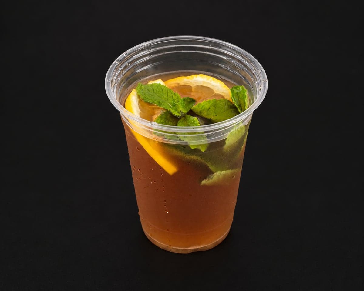 Iced Moroccan tea with fresh mint and a lemon slice in a clear cup on a matte black background